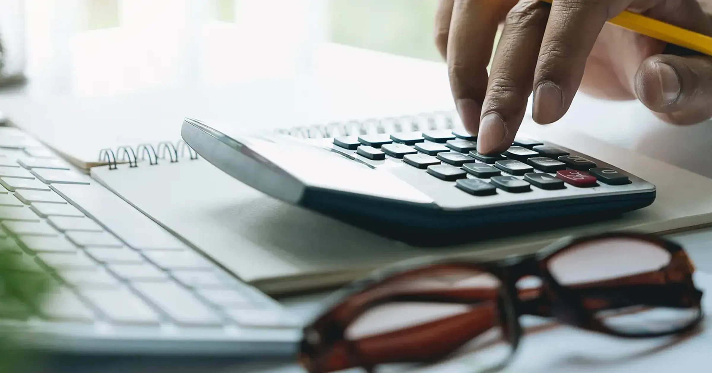 Person berechnet an einem Taschenrechner die Kosten für einen 1 MWh Batteriespeicher