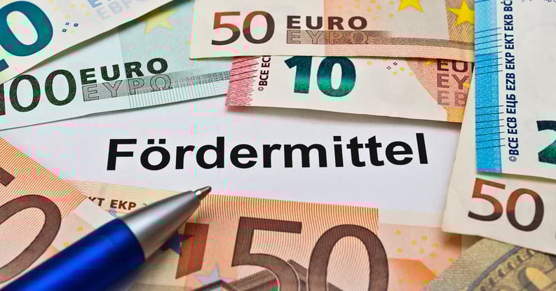 Fördermittel und Euro Banknoten zur Darstellung der Kosten für einen 1 MWh Stromspeicher und dessen Finanzierung