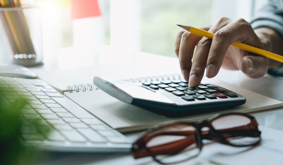 Person berechnet an einem Taschenrechner die Kosten für einen 1 MWh Batteriespeicher